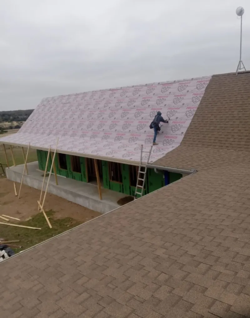 Worker preparing underlayment for a metal roof installation in Hutchins